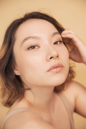 Profile young girl of Asian appearance with wavy streaked hair on beige background. Concept beauty...