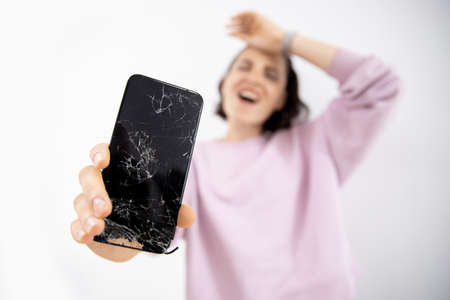 Broken glass of phone screen in hands of young woman, white backgroundの写真素材