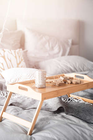 Wooden small breakfast table stands on bed in bedroom, gray sheets, sun shines through window sunriseの写真素材