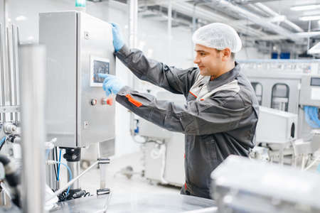 Factory engineer man operating machine control panel in dairy milk production plantの写真素材