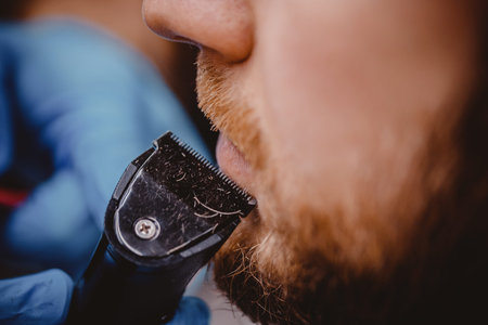 Barber with blue medical gloves protection coronavirus shearing beard to man in barbershop