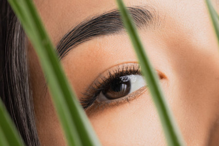 Fashion flora stylish photo of asian beautiful young woman with extended eyelashes through green...