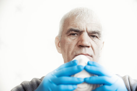 Portrait of old elderly senior man in protective mask against viruses on white backgroundの写真素材