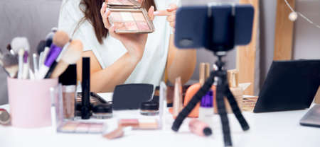 Banner online stream of beauty blogger on choice of cosmetics, recording video blog on phone home. Modern social networking conceptの写真素材