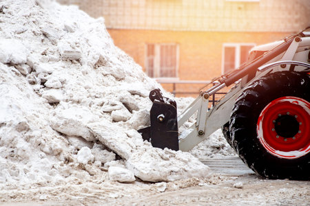 Snow removal excavator tractor cleaning on winter road covered with snow