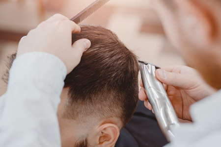Hairdresser cuts hair men in barbershop. Barber doing correct trim electric shaverの写真素材