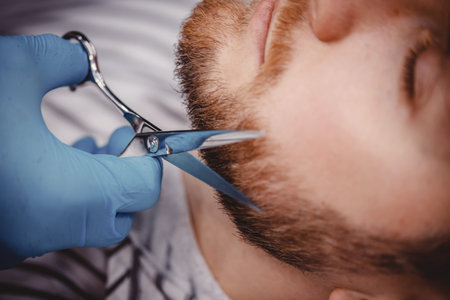 Barber with blue medical gloves protection shearing beard to man in barbershop