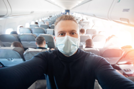 Portrait of tourist man in medical mask in airplane, concept travel trip in covid