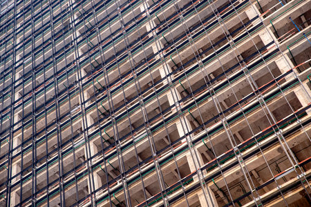 Construction site of modern apartment buildings with steel structures and cranes against blue sky...
