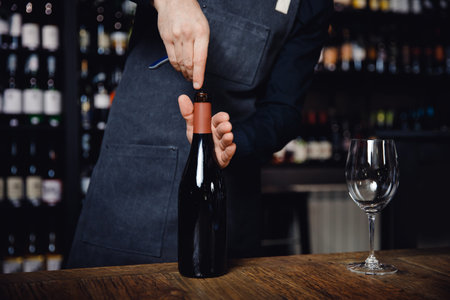 Sommelier opens cork of bottle of red wine with corkscrew