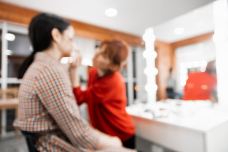 Blurred background beauty salon, master make-up artist, hairdresser girl working with client