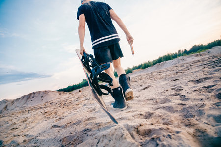 Snowboarder climbs to top of sand dune for snowboarding