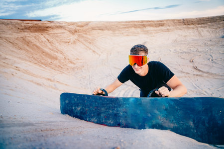 Snowboarder climbs to top of sand dune for snowboarding