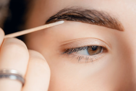 Correction and tint henna of eyebrows, master applies brush to woman marking on browの写真素材