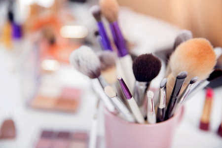 Closeup cosmetic kit makeup brushes in pink cup, white background copy spaceの写真素材