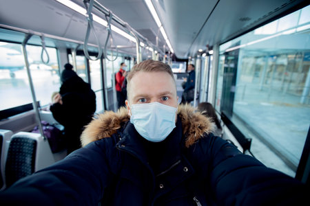 Selfie photo young male passenger wearing protective face mask while traveling by fly plane. Concept...