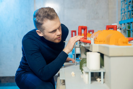 Young construction engineer man is studying layout of structure of thermal power plant with turbine