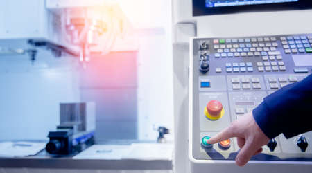Worker push start control panel of CNC machine at factory floor to get metal detail productionの写真素材