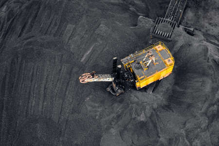 Big yellow Excavator loads coal anthracite for in open mine, aerial top viewの写真素材