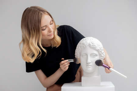 Makeup artist young woman uses brush to apply powderの写真素材