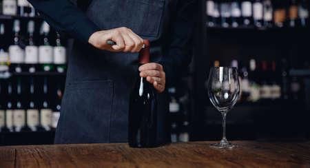 Banner Sommelier opens cork of bottle of red wine with corkscrewの写真素材