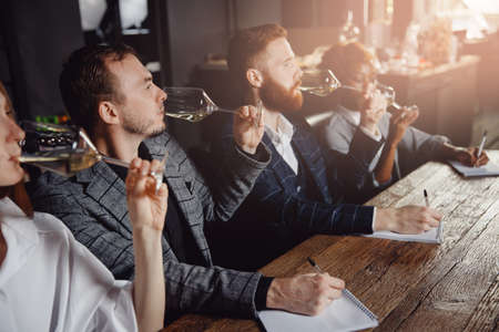 Sommeliers female and male tasting white wine and making notes at degustation card notepadの写真素材