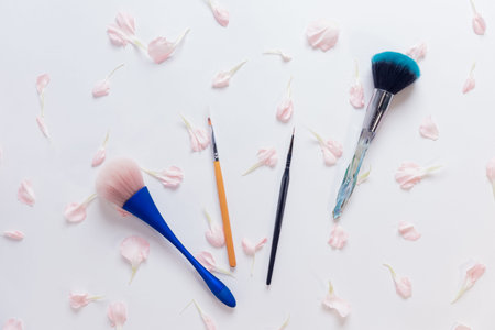 Set makeup brushes on pink flowers white color background. Top view point, flat lay