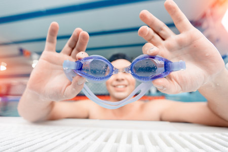 Young man swimmer teaches to put on goggles for swimming in poolの写真素材