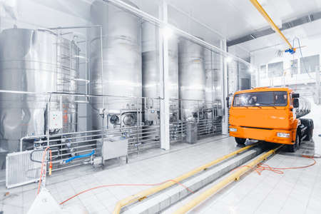 Milk tanker truck pumps products into steel storage tanks, dairy factory industryの写真素材