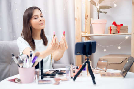 Happy woman beauty blogger recording makeup tutorial video stream on phone. Concept Influencer blog cosmeticsの写真素材
