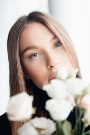 Concept beauty care skin face in salon. Portrait Caucasian Fashion of beautiful young woman green eyes with bouquet of white flowersの写真素材
