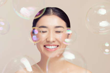 Fashion Asian happy young woman on background soap bubbles, fake eyelashes and makeupの写真素材