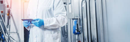 Factory worker inspecting production line bottle in of dairy plant with computer tablet. Concept food industry bannerの写真素材