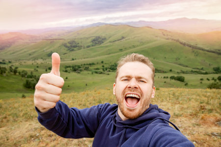 Happy young man blogger on background of mountains in summer sunset. Lifestyle scandinavian traveler...