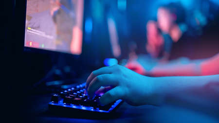 Computer sportsman plays online video games, man hand presses buttons on keyboard neonの写真素材
