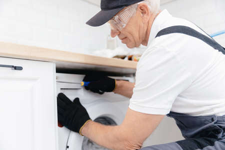 Service for repair, plumber man in uniform repairing washing machineの写真素材
