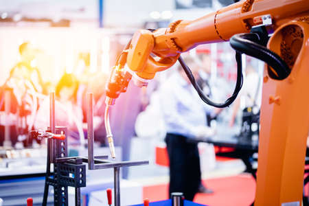Process robot hand performs welding work on metal structures industrial automatic factory, light backgroundの写真素材