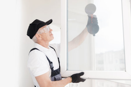 Worker man in uniform installs plastic upvc windows and doors white with vacuum lifterの写真素材