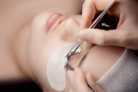 Eyelash extension procedure. Master tweezers fake 2d lashes beautiful woman eyes