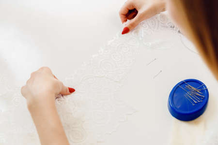 Close-up of woman seamstress cuts out lace blanks for sewing on underwear machine. Tailor designer workplace conceptの写真素材