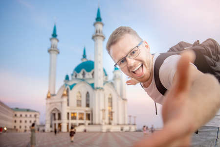 Happy man tourist with backpack takes selfie photo on background of Kul Sharif Mosque Kazan Kremlin. Concept Travel Russiaの写真素材