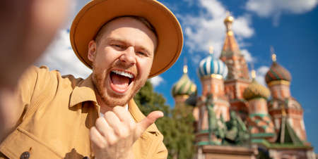 Happy Young man traveler in brown hat taking selfie on Kremlin red square in Moscow. Concept banner travel to Russiaの写真素材