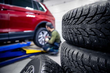 Mechanic changing wheel, replacement of winter and summer tires of modern carの写真素材