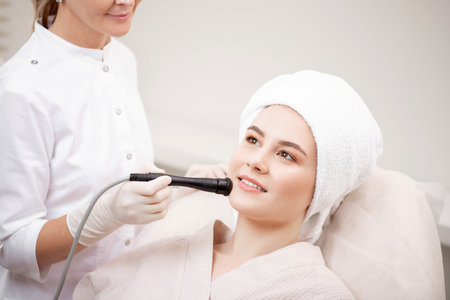 Happy young woman on rejuvenation and facelift procedure in spa clinic. Concept of smoothing expression lines and keeping skin smoothの写真素材