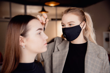 Correction and tint henna of eyebrows, master applies brush to woman marking on browの写真素材