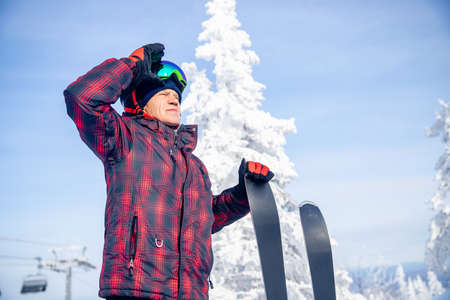Skier senior man in activewear and helmet with ski on mountain blue skyの写真素材