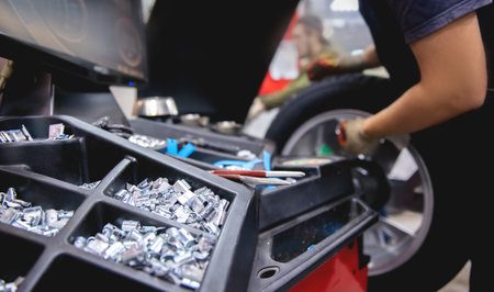 Auto mechanic places weights on steel rim of machine. Concept balancing wheel in car service