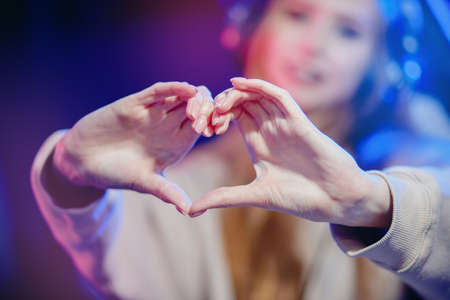 Closeup heart hands of streamer woman cyber gamer online video games showing to subscribers, blue neon colorの写真素材