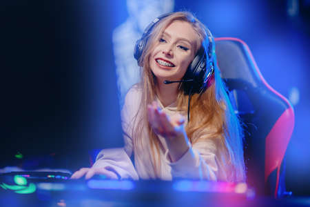 Portrait young woman happy pro gamer having live stream and playing in online video game to subscribers, blue neon colorの写真素材