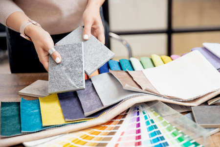 Concept design interior. Top view hand of woman designer chooses set fabrics for curtains in textileの写真素材